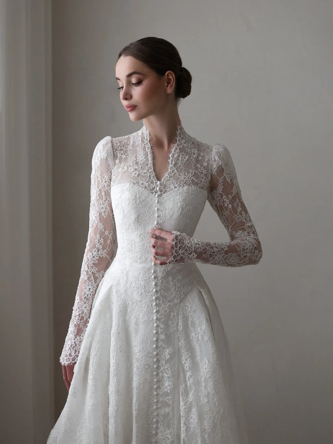 White lace bridal gown from side: button-front bodice, long sleeves, and A-line skirt