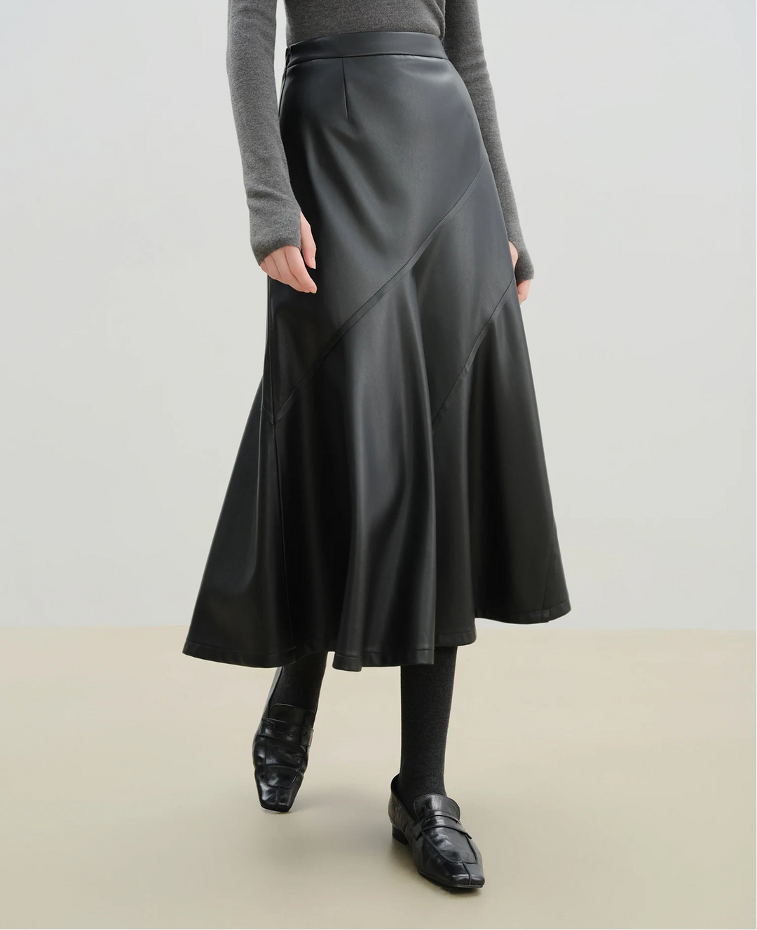 Person wearing a black leather skirt with a plain background