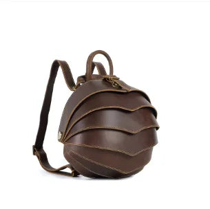 Brown leather backpack side view, curved flap and shoulder strap detail