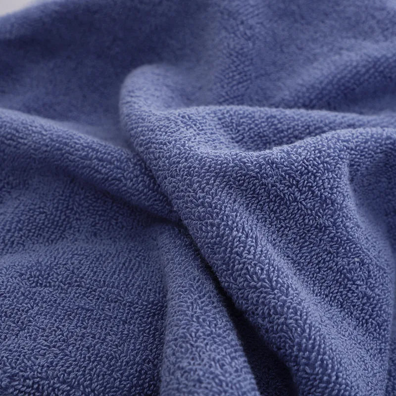 Blue terry bath towel fabric close-up with soft loop texture and folded layers