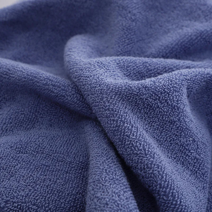 Blue terry bath towel fabric close-up with soft loop texture and folded layers