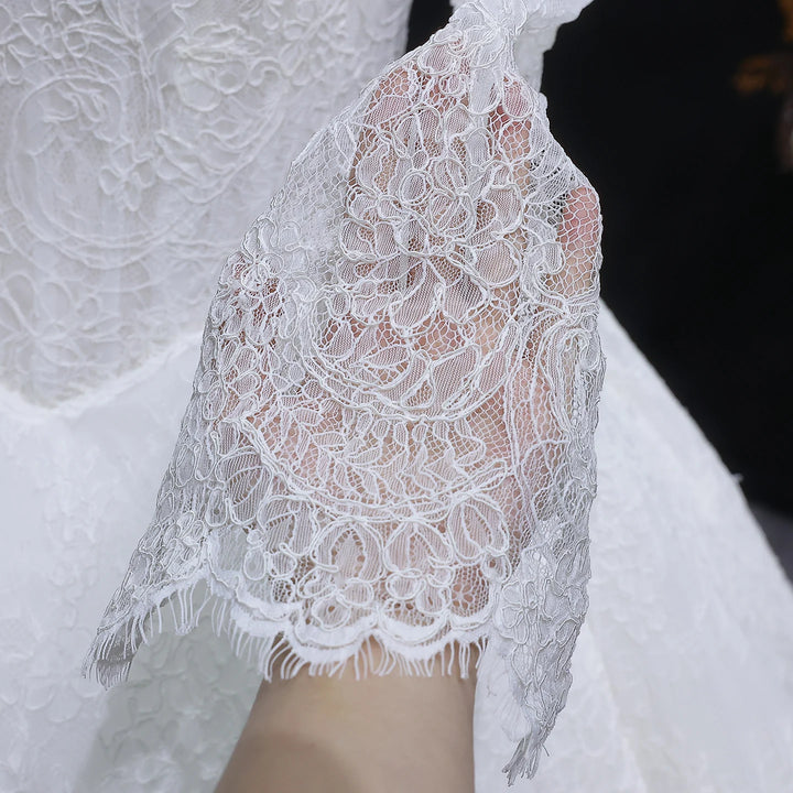 White lace wedding gown with long lace sleeves, scalloped hem, sheer lace overlay