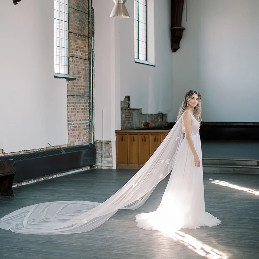 White long bridal tulle cape with butterfly appliques and draped sheer train