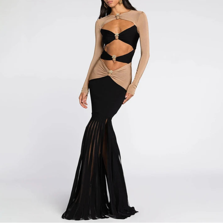 A woman wearing a dual color, long-sleeved, open belly button, floor-length dress with sequin decorations.