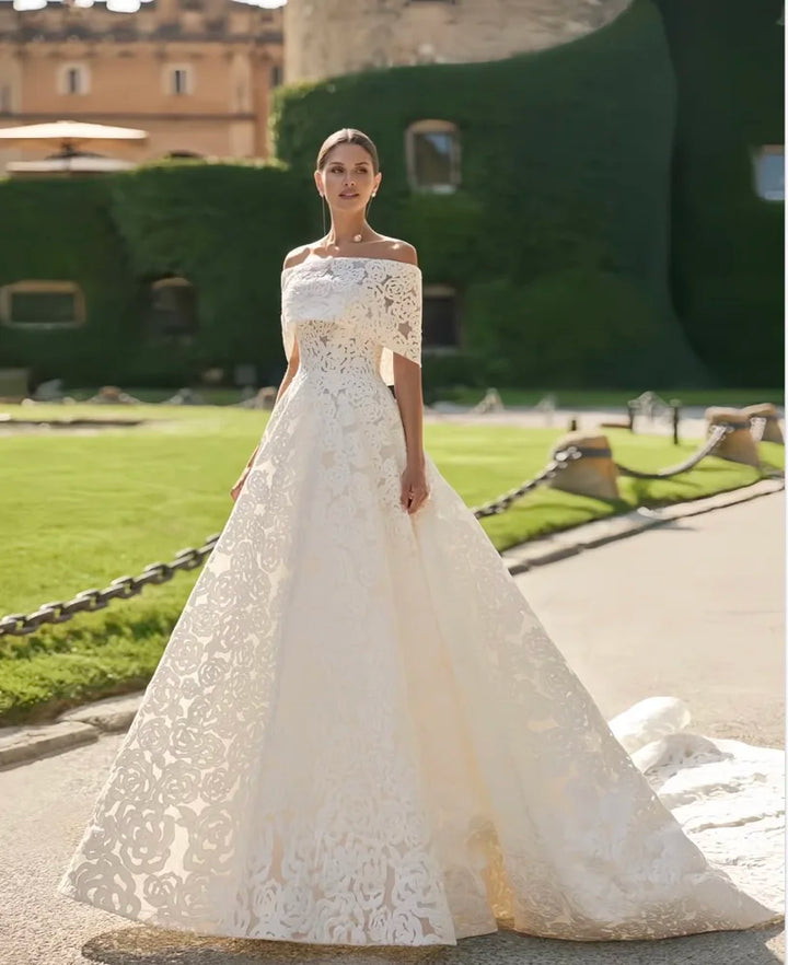 White lace bridal gown with off-shoulder square neckline and flowing A-line skirt