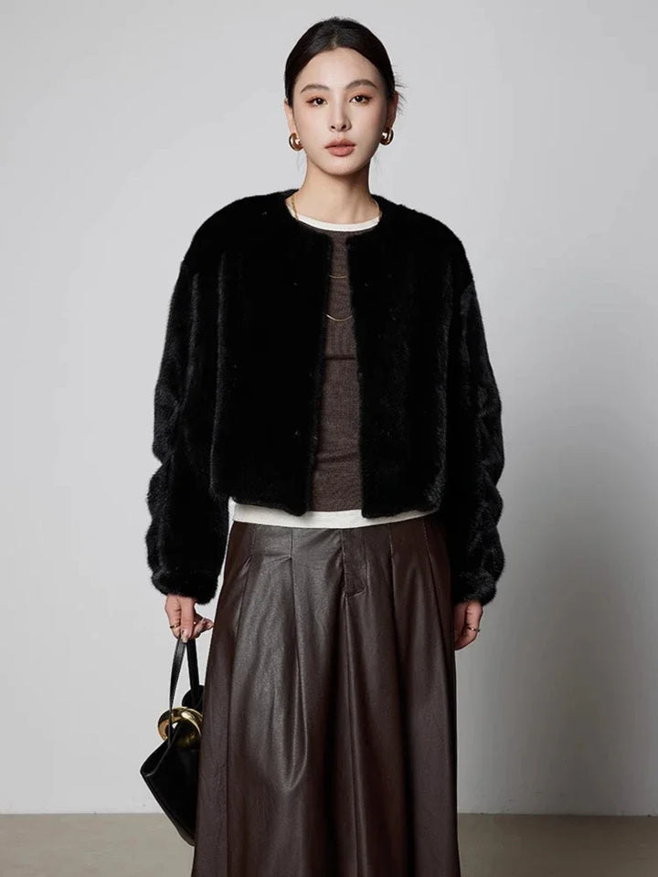 Black short mink fur coat with button front, worn over a satin skirt