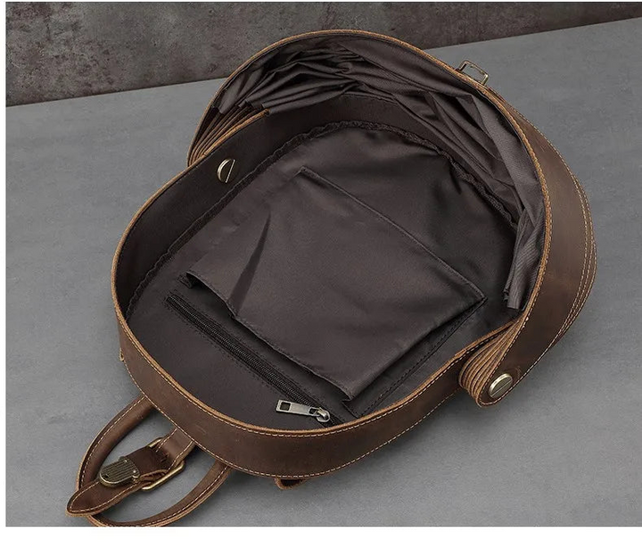 Dark brown leather backpack open to interior with zip pocket and compartments.