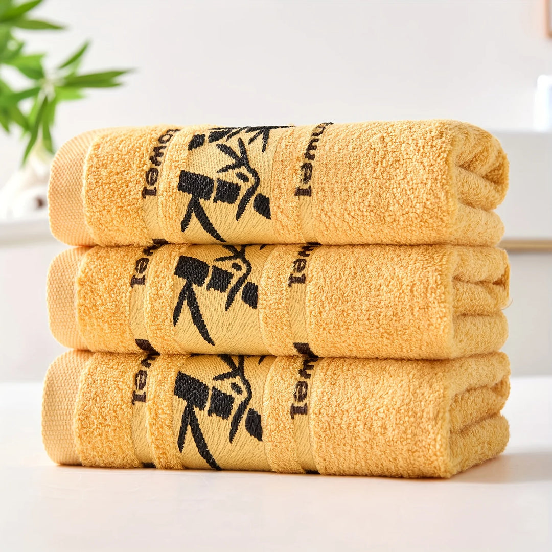 Stack of cotton bathroom towels in golden yellow with black bamboo print borders