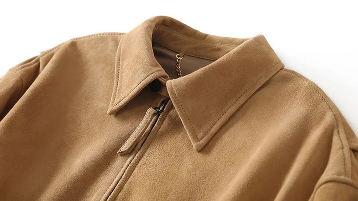Tan suede bomber jacket neckline with stand collar and visible front zipper pull.
