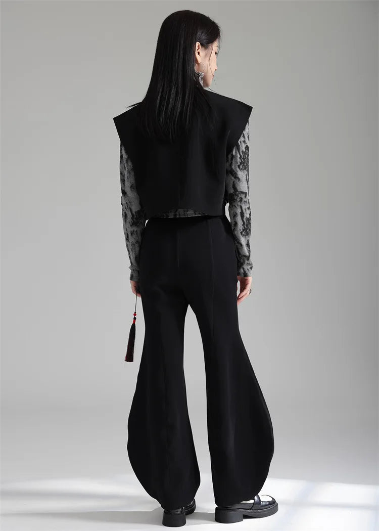 Black irregular women’s suit waistcoat, back view with wide shoulders and flared hem.