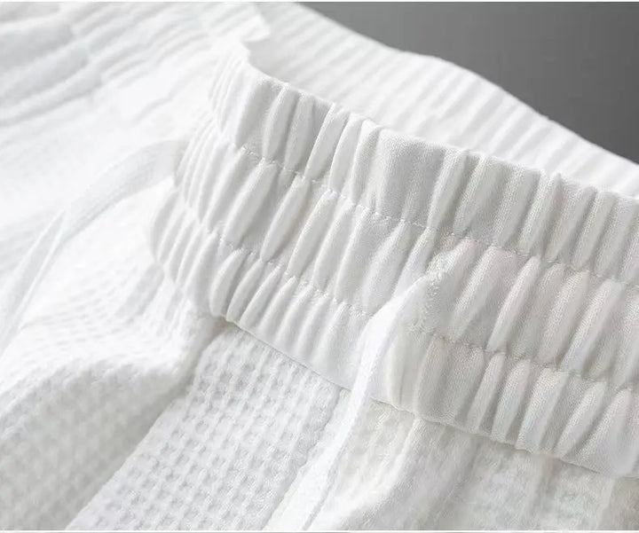 White track pants showing elastic waistband and gathered front