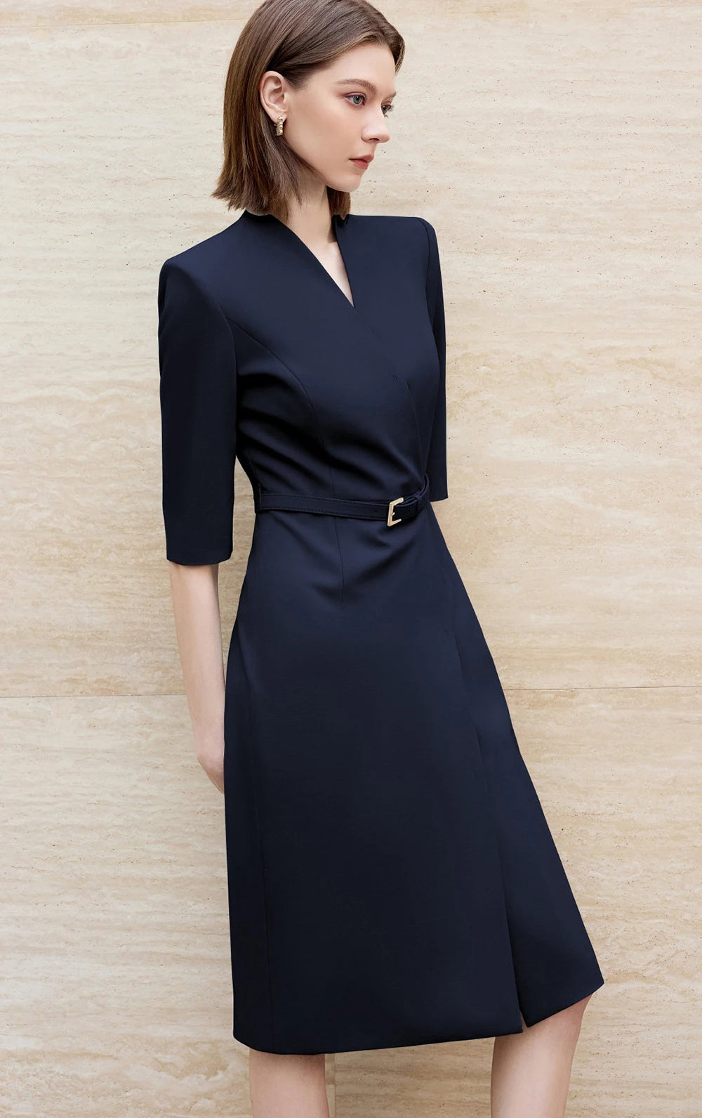 Side view of navy knee-length skirt suit dress with V-neck and waist belt