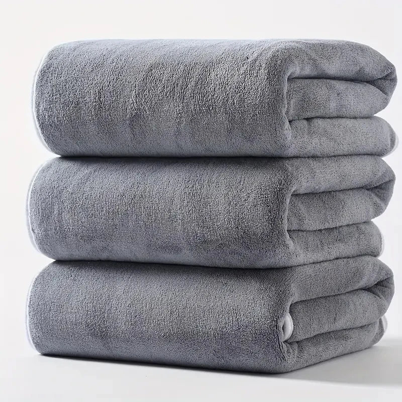 Plush velvet bath towel set in light gray, three folded towels stacked.