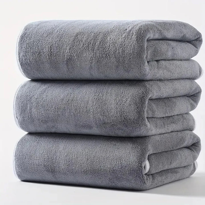 Plush velvet bath towel set in light gray, three folded towels stacked.