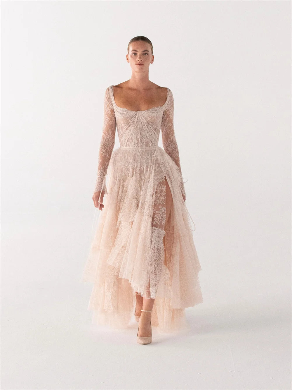 Ivory lace bridal gown front view with long sheer sleeves and tiered skirt