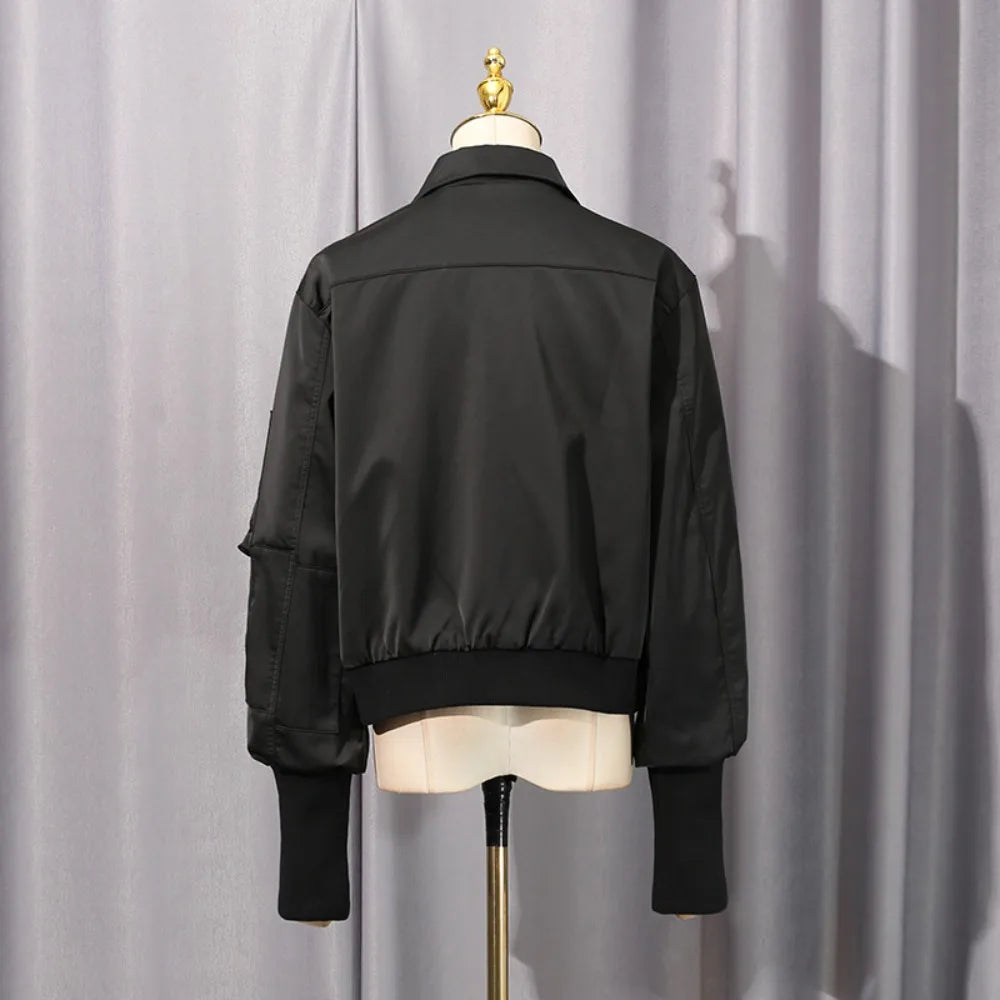 Black coat back view on mannequin, cropped length with ribbed hem and sleeve cuffs.