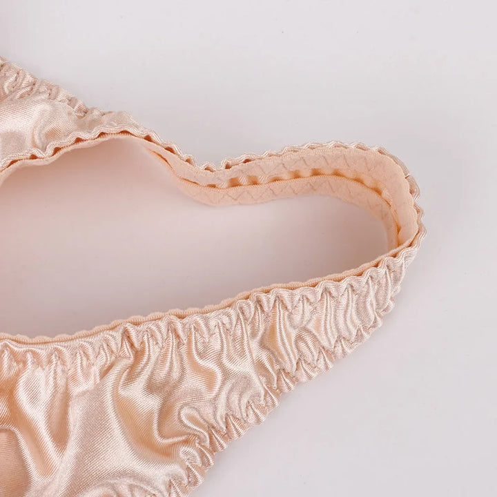 Skin-beige ruched satin bra edge with scalloped elastic trim, close-up