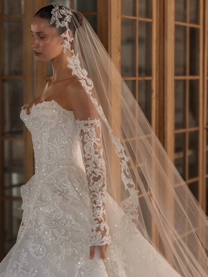 Ivory bridal lace gown with floral appliques, off-shoulder straps, and long veil