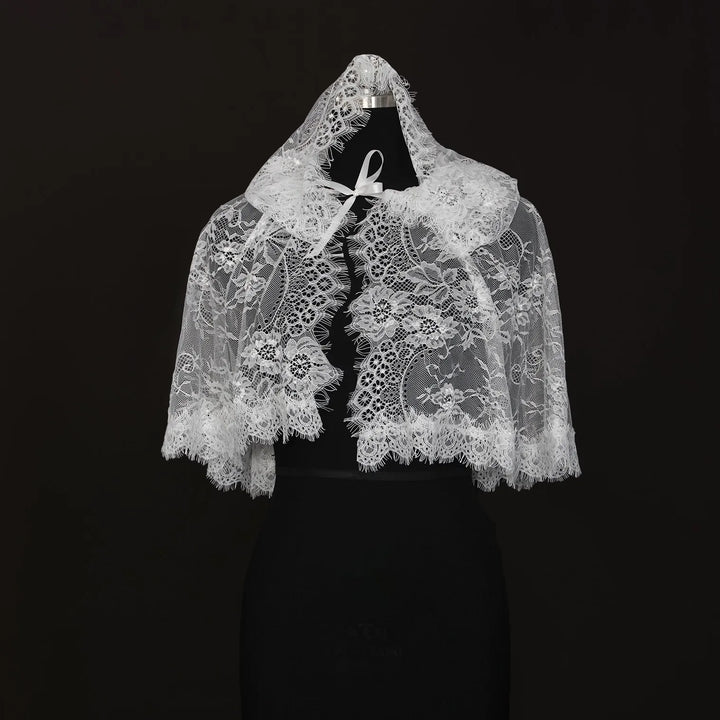 Off-white hooded lace cape on mannequin with floral lace panels and ribbon tie at front