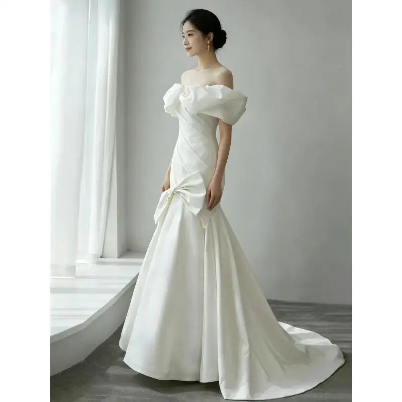 White off-shoulder satin wedding gown with draped fitted bodice and flowing A-line skirt