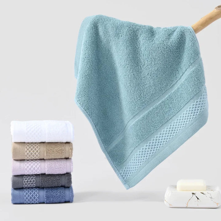Thick cotton towel set in light teal and white, with textured diamond border trim.