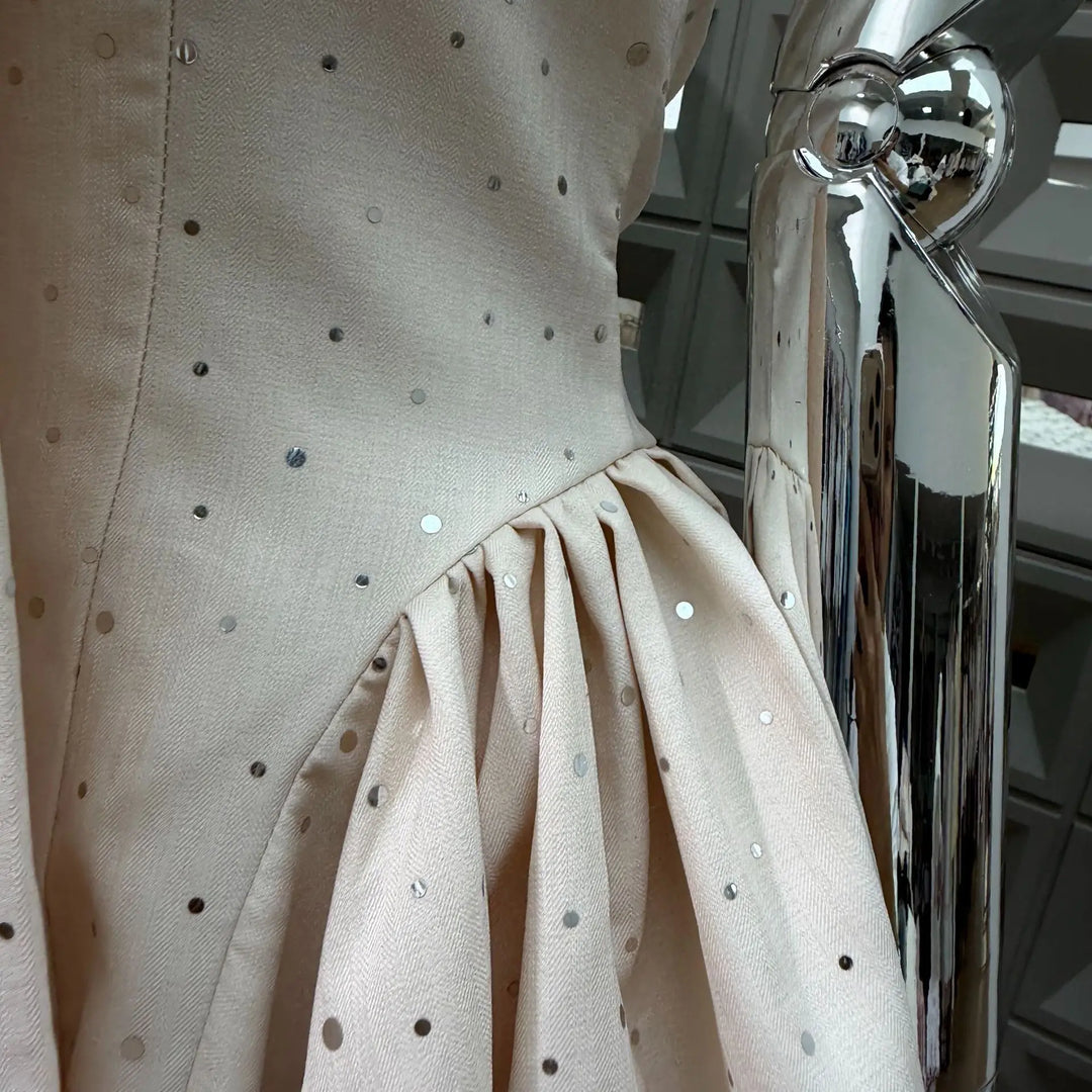 Beige polka dot mini dress on mannequin, ruched skirt with gathered flare