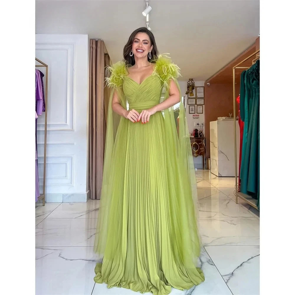 Light green formal evening gown with V-neck, pleated skirt, and feathered shoulder accents