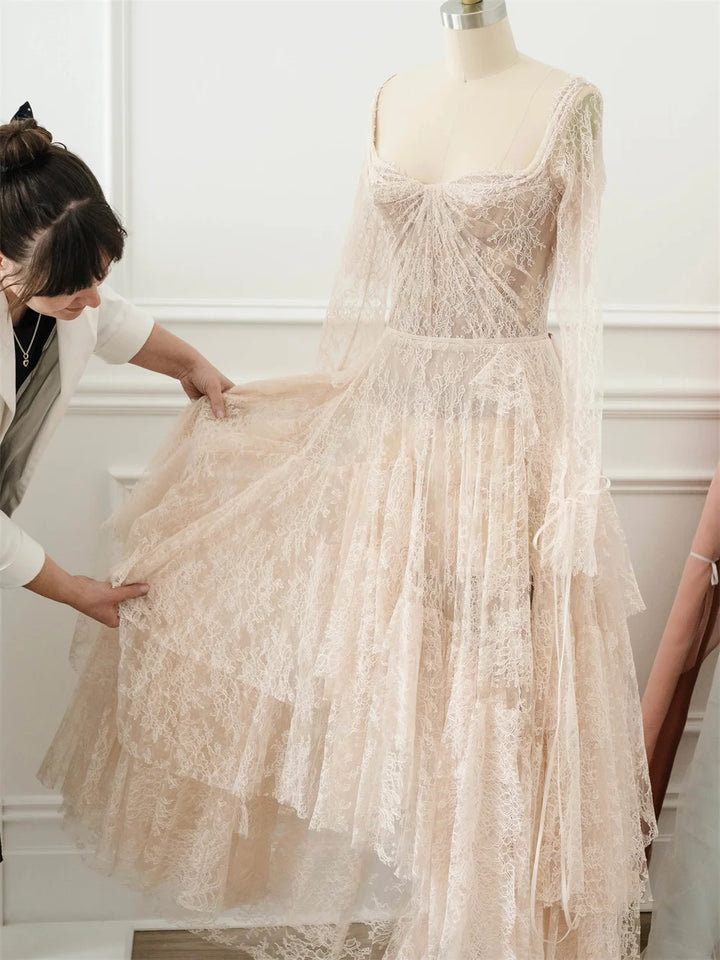 Ivory lace bridal gown mannequin with tiered skirt and long sheer sleeves