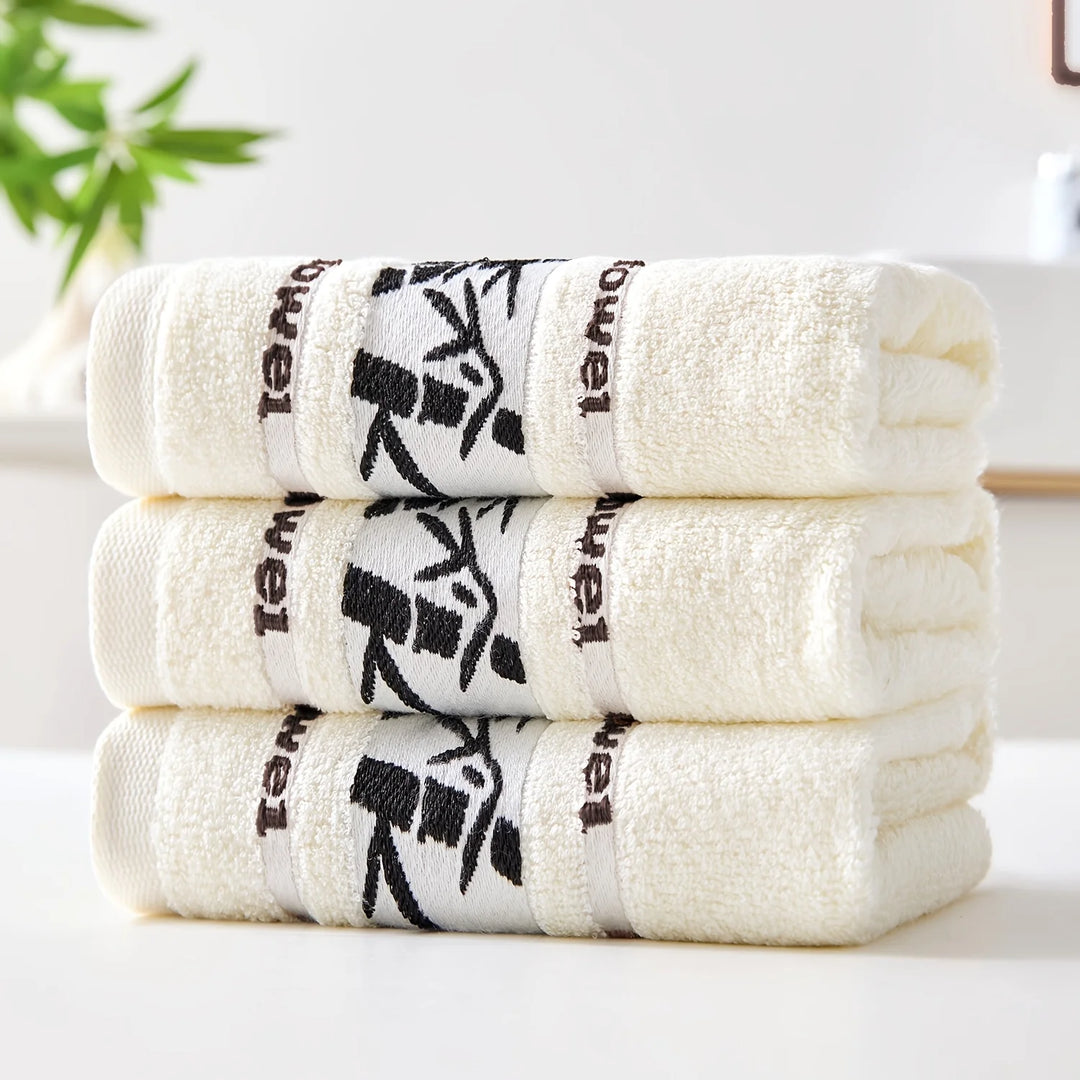 Stack of cotton bathroom towels in white with black bamboo print borders