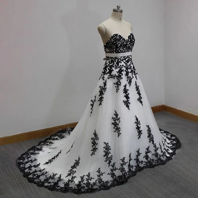White evening gown with black lace details on a mannequin against a plain background