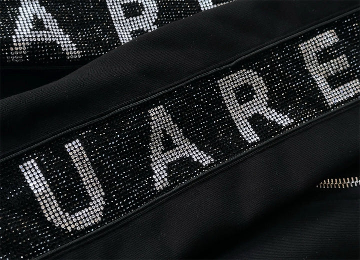 Black tracksuit jacket detail: rhinestone letter band with front zipper