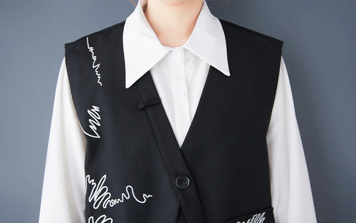 Black waistcoat close-up: V-neck lapel, button front, white scribble embroidery