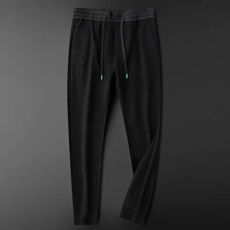 Black relaxed slim cotton track pants with elastic waist and drawstring, ankle cuff