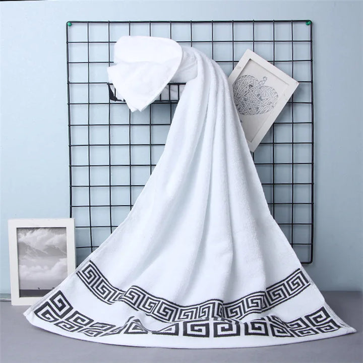 Cotton bathroom towel set in white with dark blue Greek border, folded.