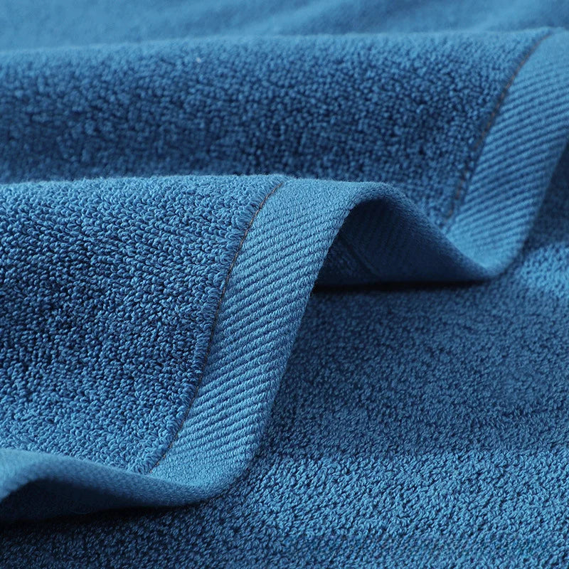Blue cotton bathroom towel with folded edge and ribbed border detail, close-up