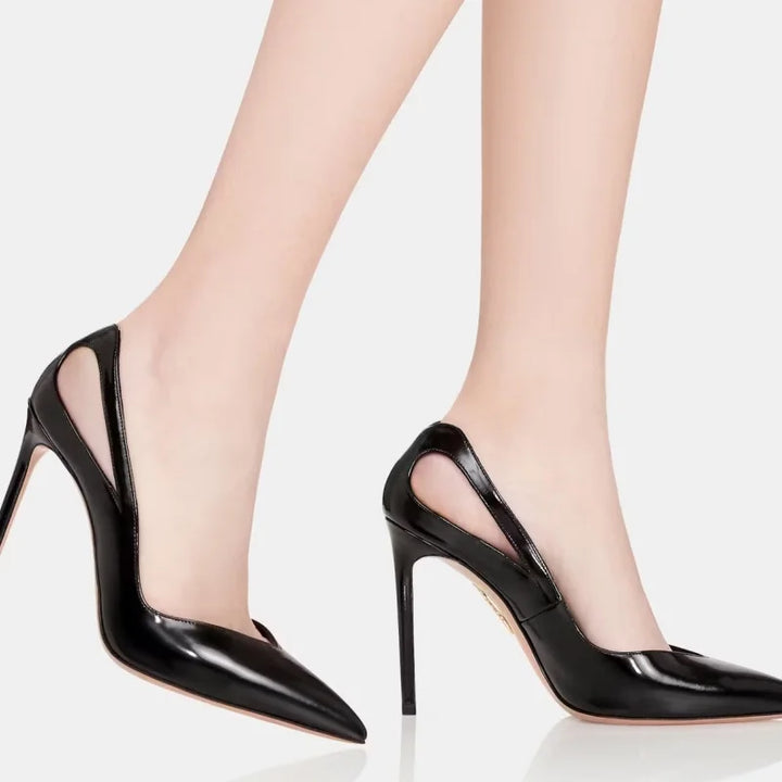 Black slip-on pointed-toe stiletto heels on legs, glossy finish