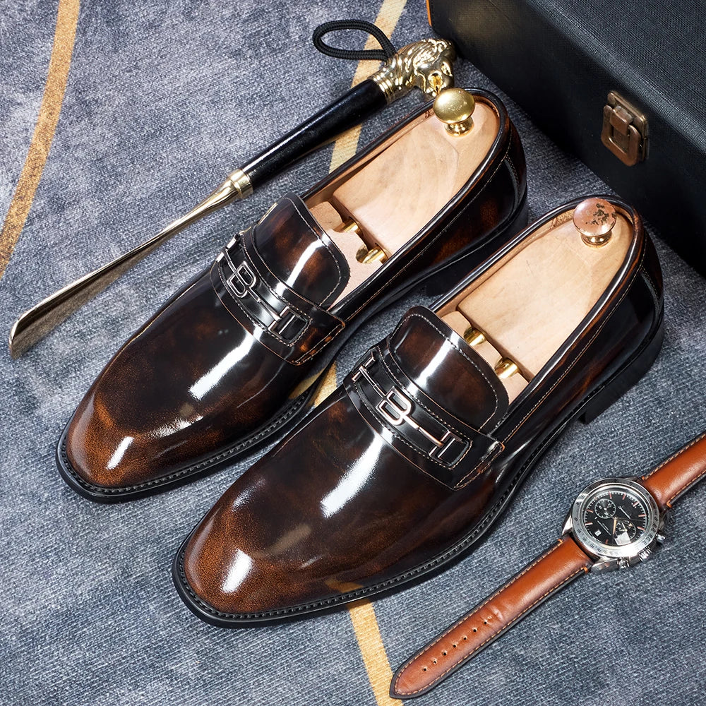 Brown pointed-toe leather loafers with metal buckle straps, top-angle view