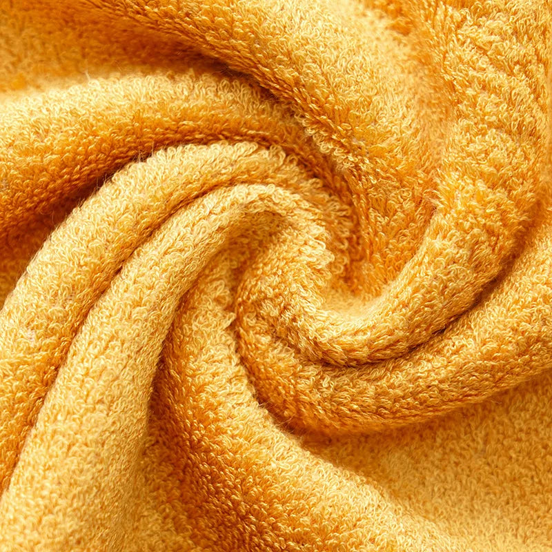 Golden yellow terry towel fabric close-up with dense looped pile and soft drape folds