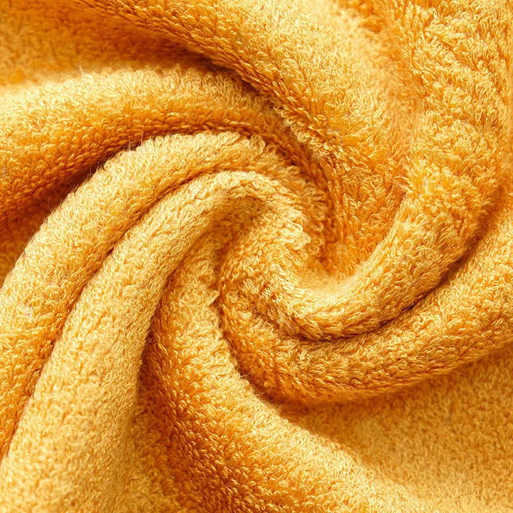 Golden yellow terry towel fabric close-up with dense looped pile and soft drape folds