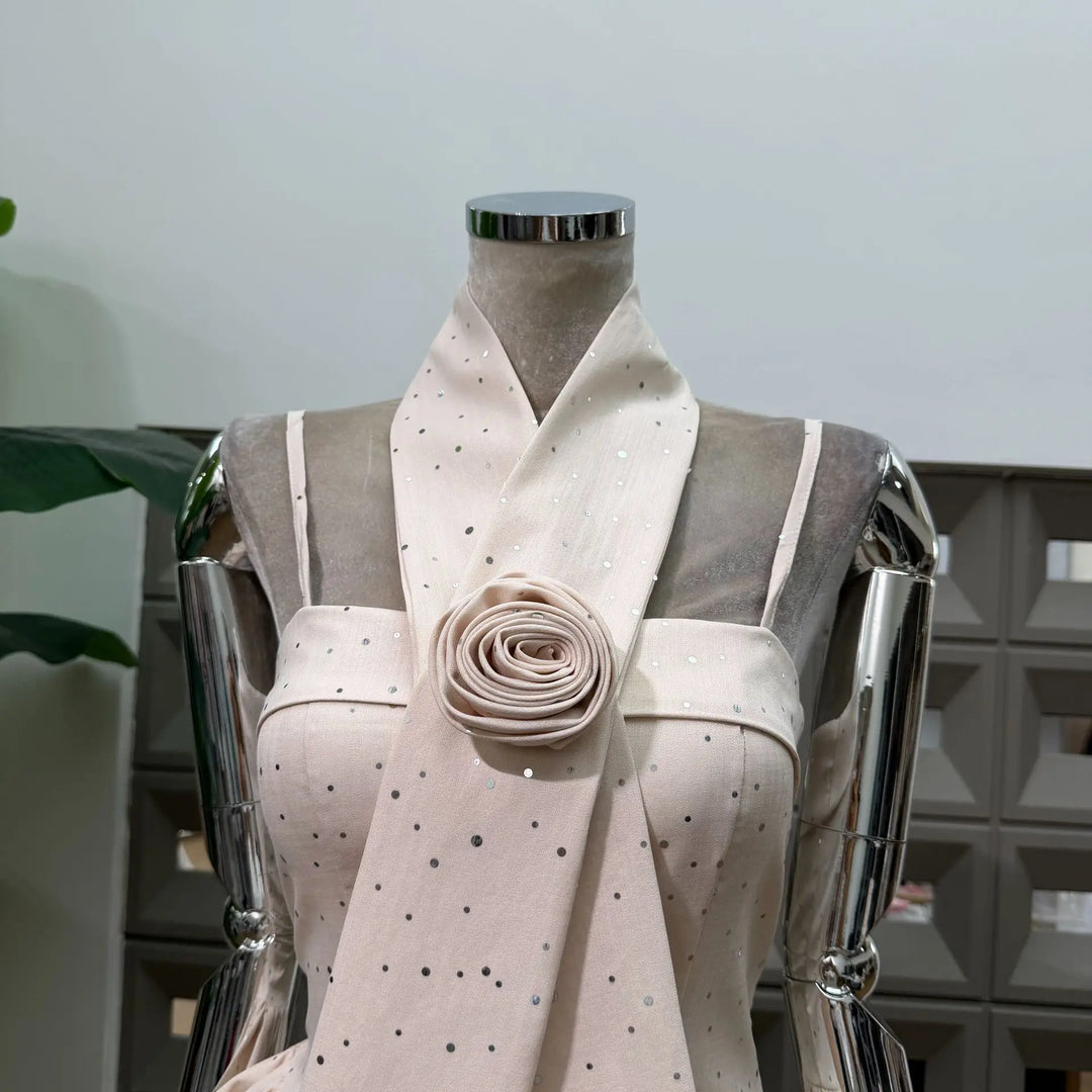 Beige polka dot mini dress detail: folded rosette at bodice waist on mannequin