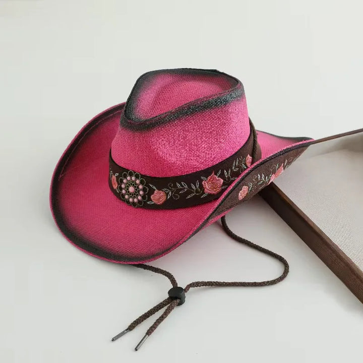 Hot pink cowboy hat with black decorative band, floral embroidery, and chin ties