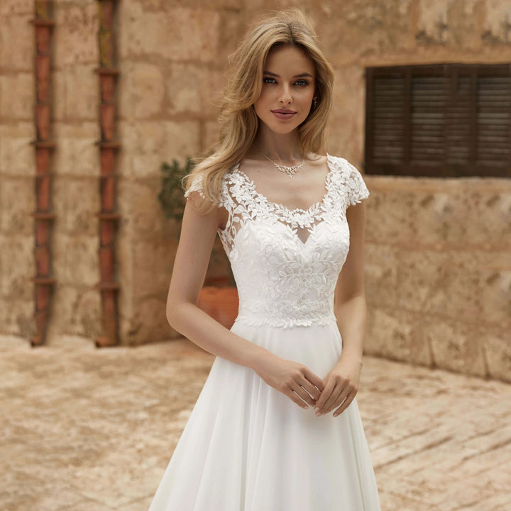 Ivory lace cap-sleeve bridal gown with scalloped V neckline and fitted bodice, front view