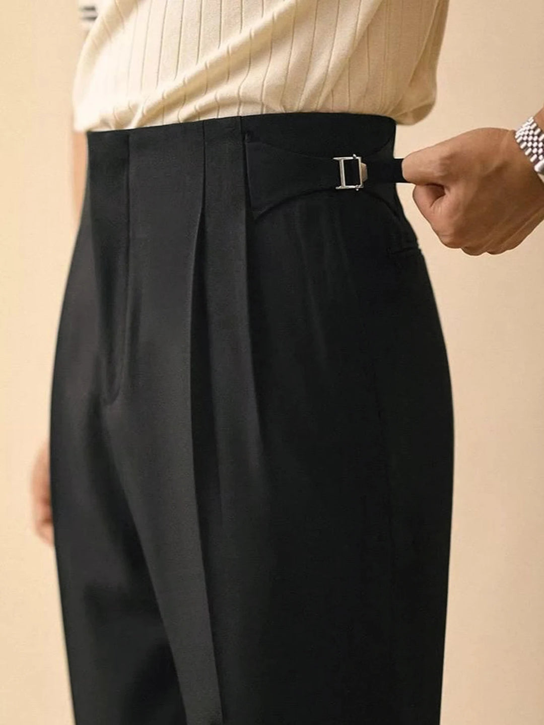 Black wide-leg pleated pants with belt loops and buckle, close-up at waistband