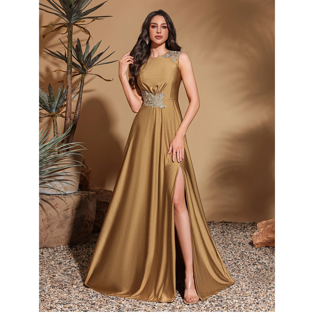 Woman in a gold evening gown with a slit standing against a neutral background