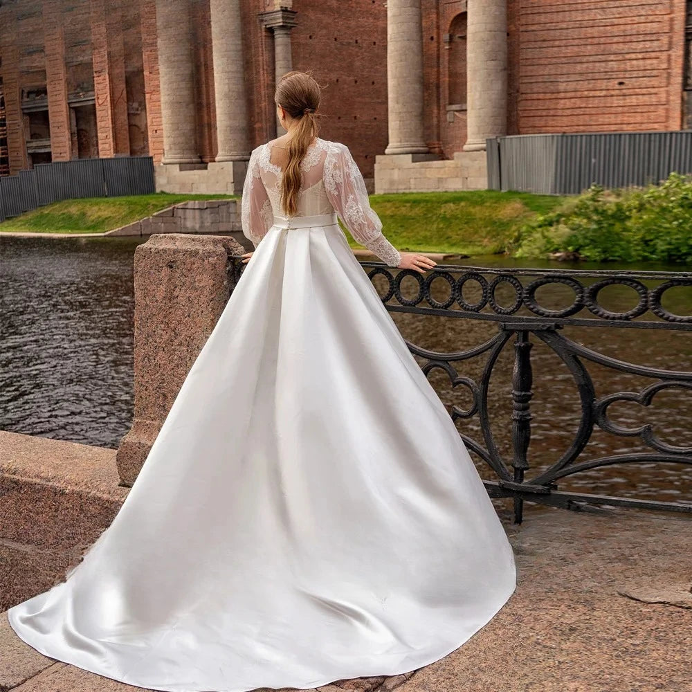 White satin A-line bridal dress, back view with lace sleeves and flowing skirt