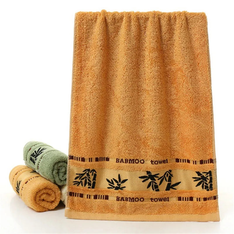 Bamboo towel set featuring an orange towel with black bamboo “Bamboo towel” band and rolled towels.