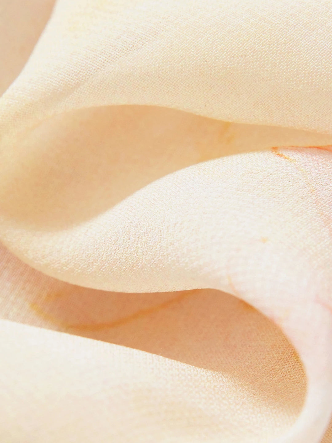 Close-up of light yellow textured fabric with soft, flowing drape