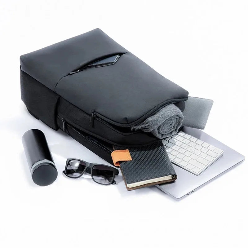 Dark travel work backpack open flat with layered storage and gear