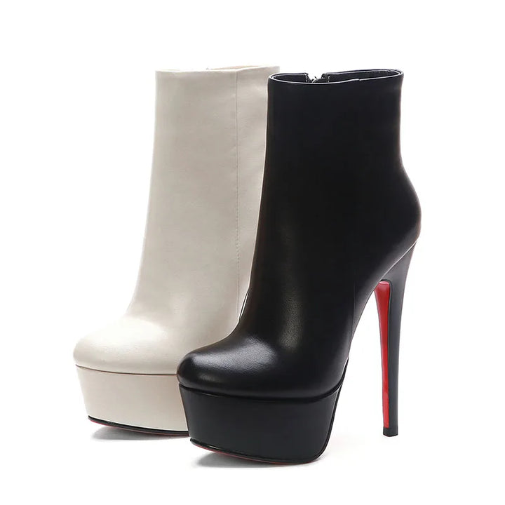 Pair of platform ankle boots with side zipper, cream and black with red heel tips.