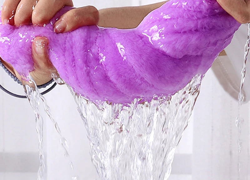 Purple plush bath towel being rinsed, hands squeezing out water